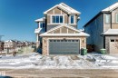Two-story residential exterior featuring a stone and siding facade, a double-car garage with paneling, multiple windows with white trim, and a gabled roofline - 3716 46 Avenue, Beaumont, AB  - Outdoor 