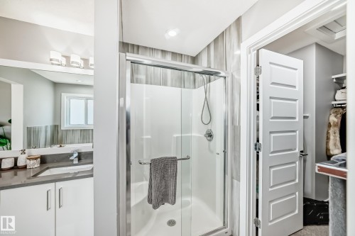 Stand-up shower with a clear glass enclosure and a full-body spray, featuring vertical-format tile surround - 3716 46 Avenue, Beaumont, AB - Indoor Photo Showing Bathroom