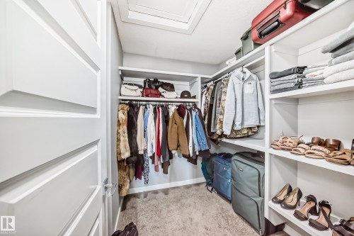 Walk-in closet featuring built-in shelving, hanging rods, and carpet flooring - 3716 46 Avenue, Beaumont, AB - Indoor With Storage