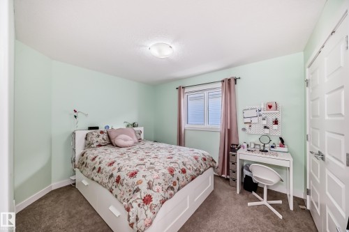 Bedroom featuring light green walls, a window with horizontal blinds, and a paneled door with contemporary hardware - 3716 46 Avenue, Beaumont, AB - Indoor Photo Showing Bedroom