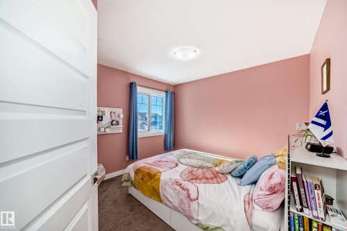 Bedroom featuring a panel door, plush carpet flooring, and a large window with blue curtains - 3716 46 Avenue, Beaumont, AB - Indoor Photo Showing Bedroom