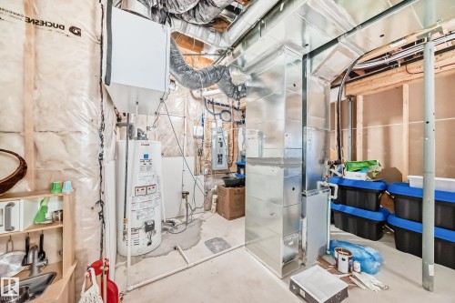 Utility room featuring exposed ductwork, a water heater, and a furnace unit - 3716 46 Avenue, Beaumont, AB - Indoor Photo Showing Basement