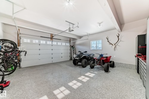 Spacious garage featuring an overhead door with transom windows, epoxy flooring, built-in storage cabinetry, and recessed lighting - 3716 46 Avenue, Beaumont, AB - Indoor Photo Showing Garage