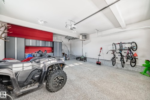 Spacious garage featuring epoxy flooring, extensive built-in cabinetry, a spiral staircase, and wall-mounted storage solutions - 3716 46 Avenue, Beaumont, AB - Indoor Photo Showing Garage