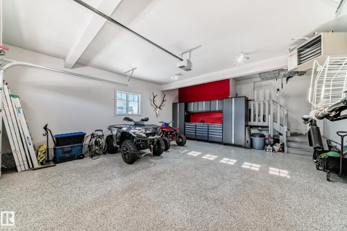 Spacious garage with epoxy flooring, built-in cabinetry, a utility sink, and recessed lighting - 3716 46 Avenue, Beaumont, AB - Indoor Photo Showing Garage