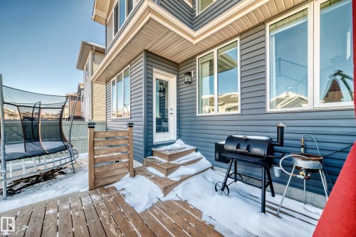 Rear exterior featuring blue horizontal siding, white trim, a wood deck, and an exterior light fixture - 3716 46 Avenue, Beaumont, AB - Outdoor With Deck Patio Veranda