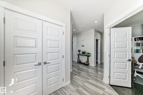 Hallway featuring wood-finish flooring, recessed lighting, and a white paneled door with contemporary hardware - 3716 46 Avenue, Beaumont, AB - Indoor Photo Showing Other Room