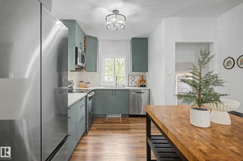 Contemporary kitchen featuring sage-toned cabinetry, stainless steel appliances, white countertops, and wood-finish flooring - 13316 109A Avenue, Edmonton, AB - Indoor Photo Showing Other Room