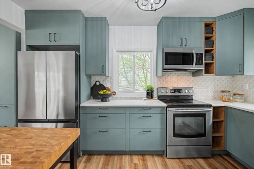 Kitchen featuring light blue cabinetry, stainless steel appliances, white countertops, and a decorative tile backsplash - 13316 109A Avenue, Edmonton, AB - Indoor Photo Showing Kitchen