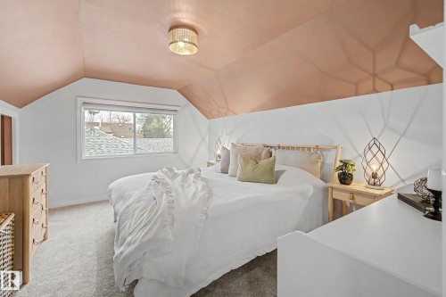 Carpeted room featuring a sloped ceiling with a flush-mount light fixture, white walls, and a window with a white frame - 13316 109A Avenue, Edmonton, AB - Indoor Photo Showing Bedroom