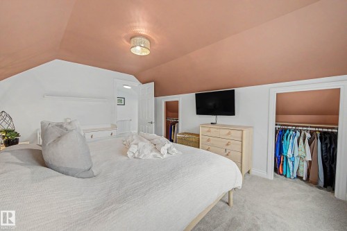 Carpeted room featuring a sloped ceiling, built-in shelving, and two recessed wardrobe areas - 13316 109A Avenue, Edmonton, AB - Indoor Photo Showing Bedroom