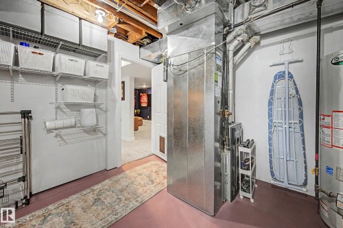 Utility area featuring a water heater, furnace system, exposed ceiling joists, and integrated wire shelving storage - 13316 109A Avenue, Edmonton, AB - Indoor Photo Showing Other Room