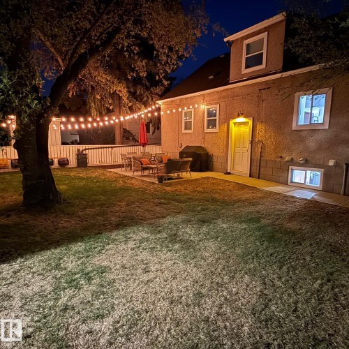 Manicured lawn with a spacious paver patio, featuring a white privacy fence and a mature tree - 13316 109A Avenue, Edmonton, AB - Outdoor