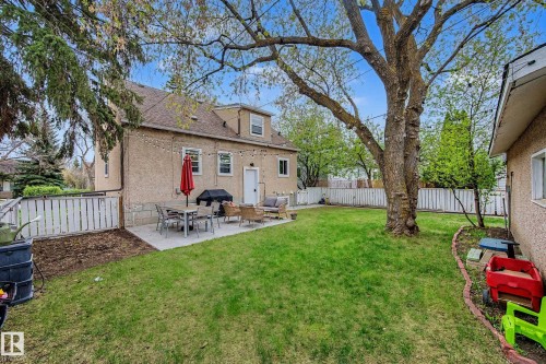 Expansive backyard featuring a concrete patio, mature trees, manicured lawn, and perimeter fencing - 13316 109A Avenue, Edmonton, AB - Outdoor With Exterior