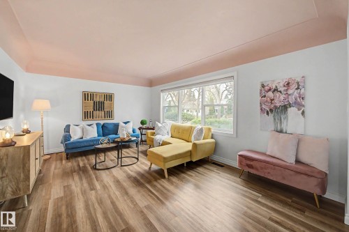 Bright living space featuring wood-finish flooring, a large bay window, and a tray ceiling with a contrasting soffit detail - 13316 109A Avenue, Edmonton, AB - Indoor Photo Showing Living Room