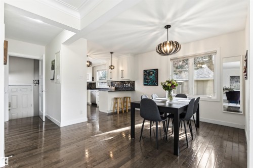 Open-concept dining area featuring wood-finish flooring, a modern chandelier, and a large window - 14608 97 Avenue, Edmonton, AB - Indoor Photo Showing Dining Room
