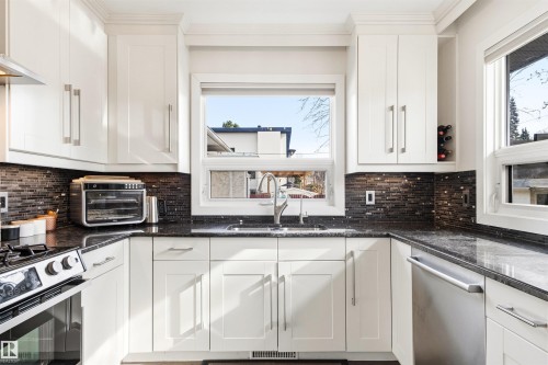 Kitchen featuring white cabinetry, dark speckled countertops, a dark mosaic tile backsplash, and stainless steel appliances - 14608 97 Avenue, Edmonton, AB - Indoor Photo Showing Kitchen With Stainless Steel Kitchen With Upgraded Kitchen