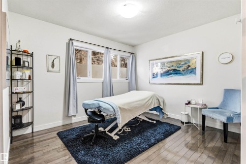Brightly lit room featuring wood-finish flooring, white walls, and multiple windows with drapes - 14608 97 Avenue, Edmonton, AB - Indoor Photo Showing Bedroom