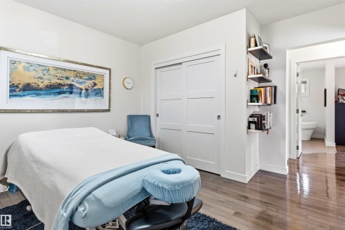 Interior room featuring wood-finish flooring, white walls, and a large sliding closet with panel doors - 14608 97 Avenue, Edmonton, AB - Indoor Photo Showing Bedroom