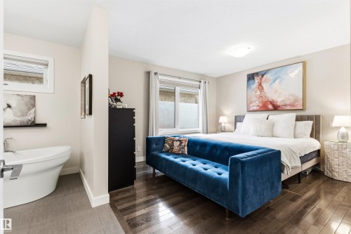 Spacious bedroom featuring wood-finish flooring, light neutral walls, and a freestanding soaking tub - 14608 97 Avenue, Edmonton, AB - Indoor Photo Showing Bedroom