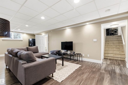 Spacious lower-level living area featuring wood-finish flooring, recessed lighting, and a drop ceiling - 14608 97 Avenue, Edmonton, AB - Indoor