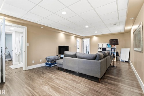 Spacious entertainment area featuring wood-finish flooring, recessed lighting, and a drop ceiling - 14608 97 Avenue, Edmonton, AB - Indoor