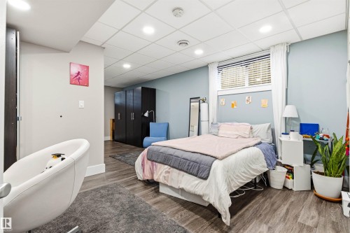 Spacious room featuring wood-finish flooring, a drop ceiling with recessed lighting, and light blue wall accents - 14608 97 Avenue, Edmonton, AB - Indoor Photo Showing Bedroom