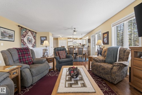 Spacious living area featuring wood-finish flooring, ample natural light from large windows, and a dedicated dining space - 77 Lakeshore Drive, Rural Leduc County, AB - Indoor Photo Showing Living Room