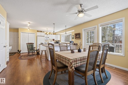Bright dining area featuring wood-finish flooring, a ceiling fan with light fixture, and multiple windows - 77 Lakeshore Drive, Rural Leduc County, AB - Indoor Photo Showing Dining Room