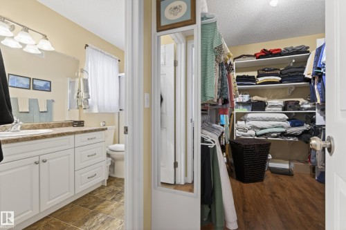 Bathroom featuring a white vanity with a brown speckled countertop, under-mount sink, and chrome fixtures - 77 Lakeshore Drive, Rural Leduc County, AB - Indoor Photo Showing Bathroom