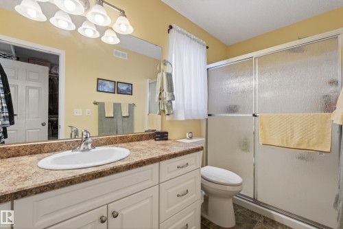 Bathroom featuring a vanity with a laminate countertop, an oval undermount sink, and white cabinetry - 77 Lakeshore Drive, Rural Leduc County, AB - Indoor Photo Showing Bathroom