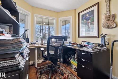 Office space featuring two large windows, wood-finish flooring, a built-in desk, and light-toned walls - 77 Lakeshore Drive, Rural Leduc County, AB - Indoor Photo Showing Office
