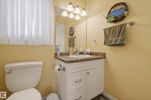 Bathroom featuring a white vanity with a brown countertop, an undermount sink, and a mirrored medicine cabinet - 77 Lakeshore Drive, Rural Leduc County, AB - Indoor Photo Showing Bathroom