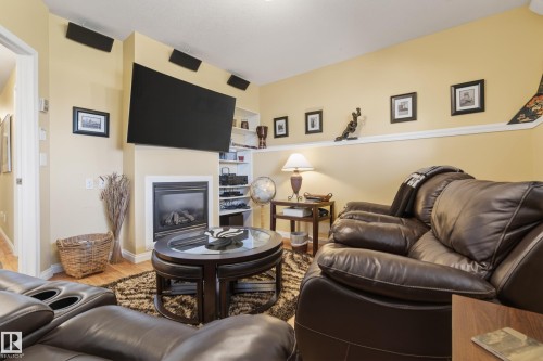 Living area featuring a built-in fireplace with a white surround, integrated shelving, and wood-finish flooring - 77 Lakeshore Drive, Rural Leduc County, AB - Indoor Photo Showing Living Room With Fireplace