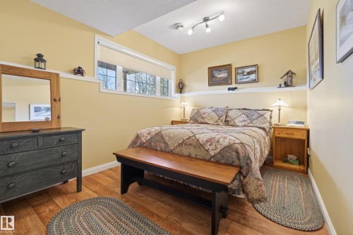 Bedroom with wood-finish flooring, light yellow walls, and a white chair rail - 77 Lakeshore Drive, Rural Leduc County, AB - Indoor Photo Showing Bedroom