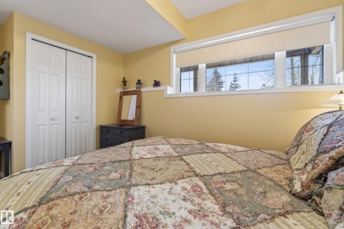 Bedroom featuring high-set transom windows, a bi-fold closet with panel doors, and a built-in wall shelf - 77 Lakeshore Drive, Rural Leduc County, AB - Indoor Photo Showing Bedroom