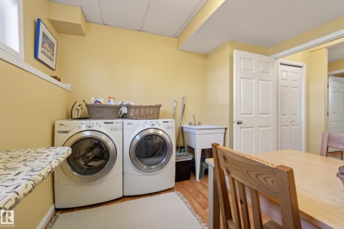 Dedicated laundry area featuring a utility sink, wood-finish flooring, and a drop ceiling - 77 Lakeshore Drive, Rural Leduc County, AB - Indoor Photo Showing Laundry Room