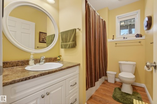 Vanity with a white oval sink, wood-finish countertop, and white cabinetry - 77 Lakeshore Drive, Rural Leduc County, AB - Indoor Photo Showing Bathroom