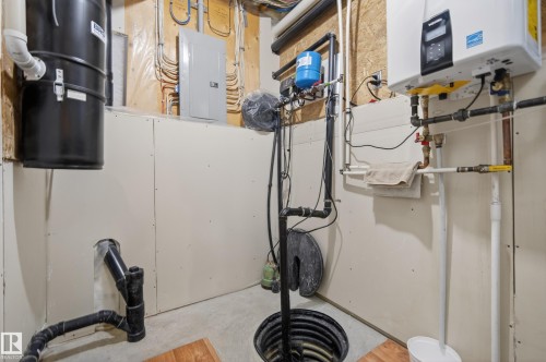 Utility area featuring a water heater, central vacuum system, sump pump, and electrical panel - 77 Lakeshore Drive, Rural Leduc County, AB - Indoor Photo Showing Basement