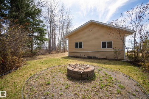 Backyard area featuring a circular brick fire pit, a gravel path, and a grass lawn - 77 Lakeshore Drive, Rural Leduc County, AB - Outdoor