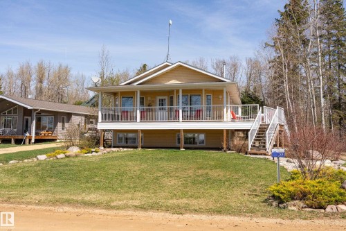 Yellow exterior with white trim, featuring a covered elevated deck with white railings and a side staircase - 77 Lakeshore Drive, Rural Leduc County, AB - Outdoor With Deck Patio Veranda With Facade