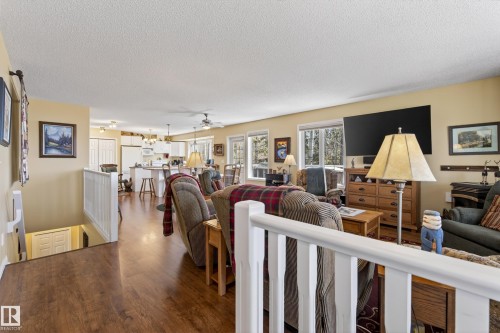 Open-concept living space featuring wood-finish flooring, a white railing system, and recessed lighting - 77 Lakeshore Drive, Rural Leduc County, AB - Indoor