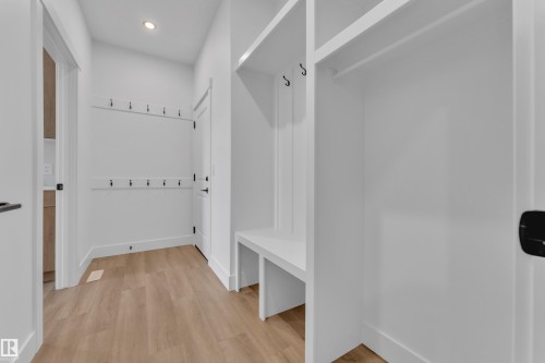 Entryway featuring built-in white cabinetry, integrated bench seating, and wood-finish flooring - 13128 187 Avenue, Edmonton, AB - Indoor Photo Showing Other Room