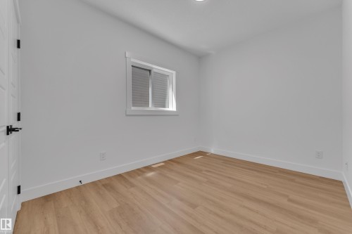 Bright interior space featuring wood-finish flooring, white baseboards, and a window with blinds - 13128 187 Avenue, Edmonton, AB - Indoor Photo Showing Other Room