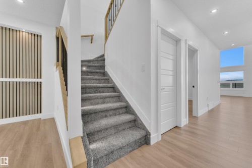 Light gray carpeted staircase featuring contemporary black metal and wood railings - 13128 187 Avenue, Edmonton, AB - Indoor Photo Showing Other Room