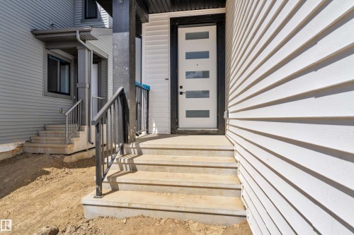 Modern entryway featuring a white door with horizontal lites, concrete steps, and black metal railings - 13128 187 Avenue, Edmonton, AB - Outdoor With Exterior
