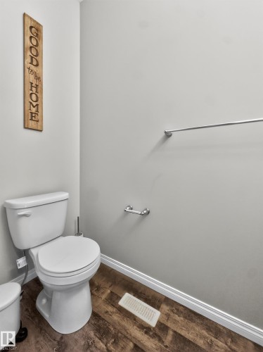 Bathroom featuring a white toilet, chrome towel bar, and wood-look flooring - 15 2072 Wonnacott Way, Edmonton, AB - Indoor Photo Showing Bathroom