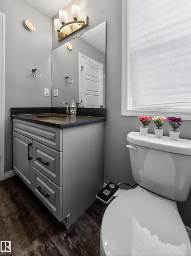 The bathroom features a vanity with a dark countertop and a white toilet - 15 2072 Wonnacott Way, Edmonton, AB - Indoor Photo Showing Bathroom
