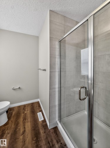 Bathroom featuring a glass-enclosed shower with tiled walls and a toilet - 15 2072 Wonnacott Way, Edmonton, AB - Indoor Photo Showing Bathroom
