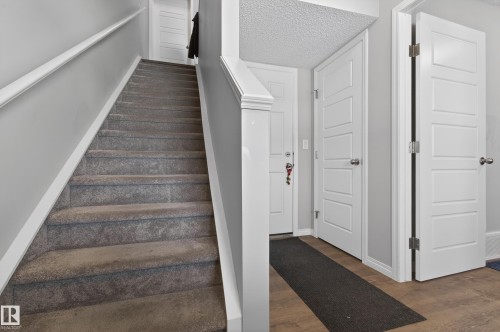 Entryway featuring a carpeted staircase with white trim, light grey walls, and doors with white paneling - 15 2072 Wonnacott Way, Edmonton, AB - Indoor Photo Showing Other Room